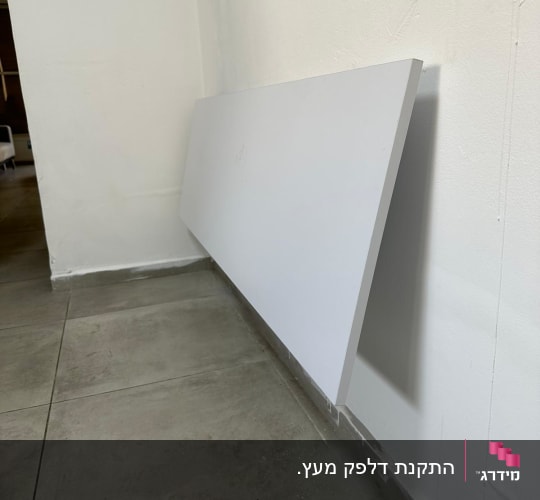 לוח עץ לבן מונח על קיר לבן